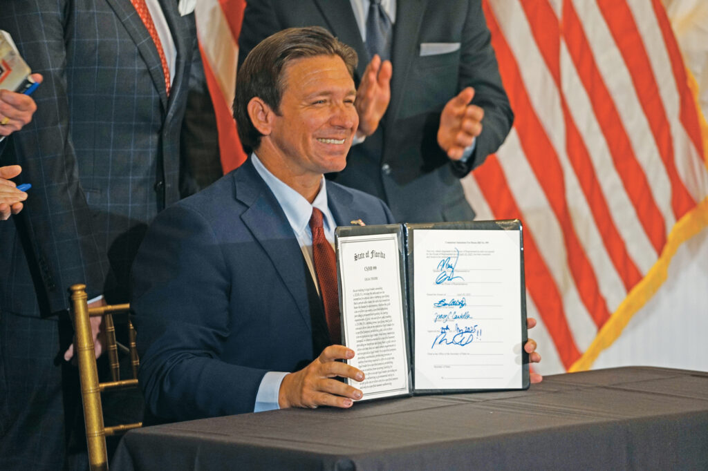 Ron DeSantis, Governor of Florida, smiles after signing House Bill 999 while a crowd of supporters cheer at Highland Manor in Apopka.