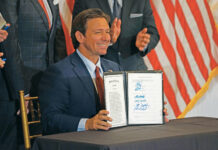 Ron DeSantis, Governor of Florida, smiles after signing House Bill 999 while a crowd of supporters cheer at Highland Manor in Apopka.