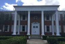Brick building with multiple windows and columns and works "Apopka City Hall" on the front.