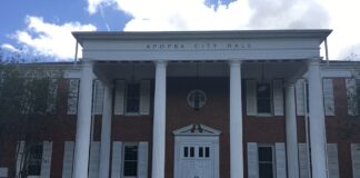 Brick building with multiple windows and columns and works "Apopka City Hall" on the front.