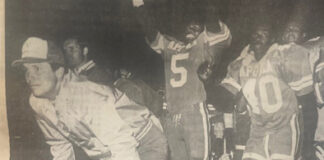 Coach Chip Gierke watches a play finish while players of his celebrate.