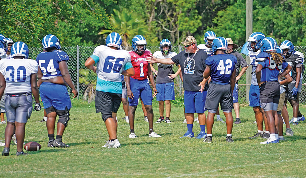 Former head coach of the Blue Darter football team, Jeff Rolson, talks with Tyson Davison (1) and a running back during spring practice in May.