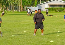 Former president of Apopka Pop Warner, Tony Shuler (c), encourages his players during a shuttle drill.