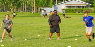 Former president of Apopka Pop Warner, Tony Shuler (c), encourages his players during a shuttle drill.