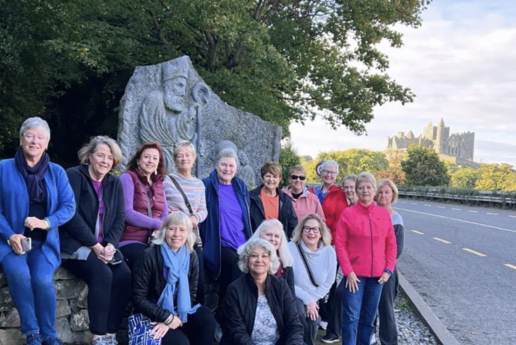 A group of women gather together and smiling. In the background is a castle.