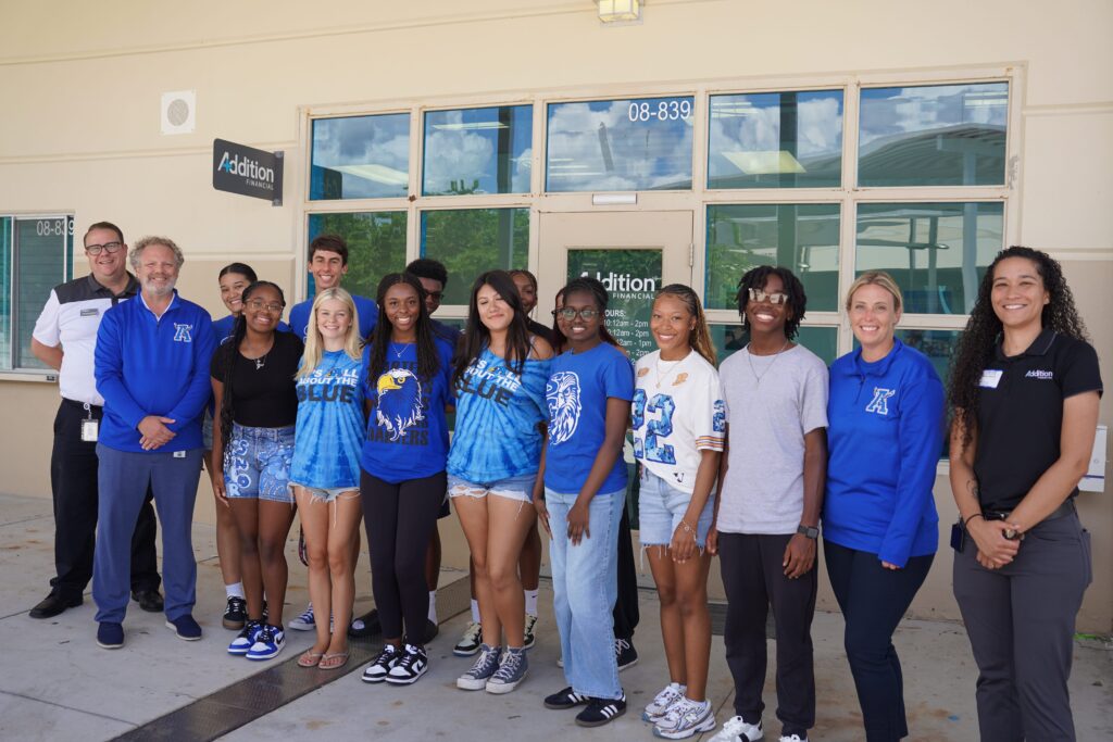 All of the Apopka High School students in this photo were selected to run the on-campus Addition Financial Credit Union on-campus branch for the 2025-26 school year. Pictured with them are Aaron Sanders (L), senior public relations specialist for Addition Financial; Lyle Heinz (2nd from L), principal of Apopka High School; and Marissa Edwards (R), the team lead for Addition Financial’s High School Branches department.