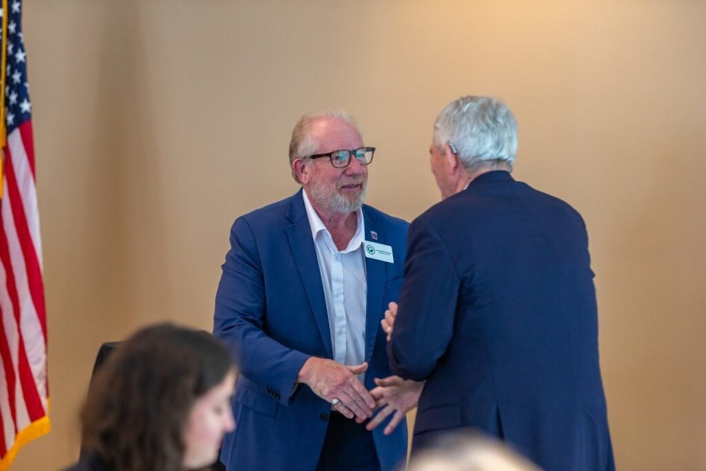 Nick Grounds (L) shakes hands with Congressman Daniel Webster at a chamber event this month.