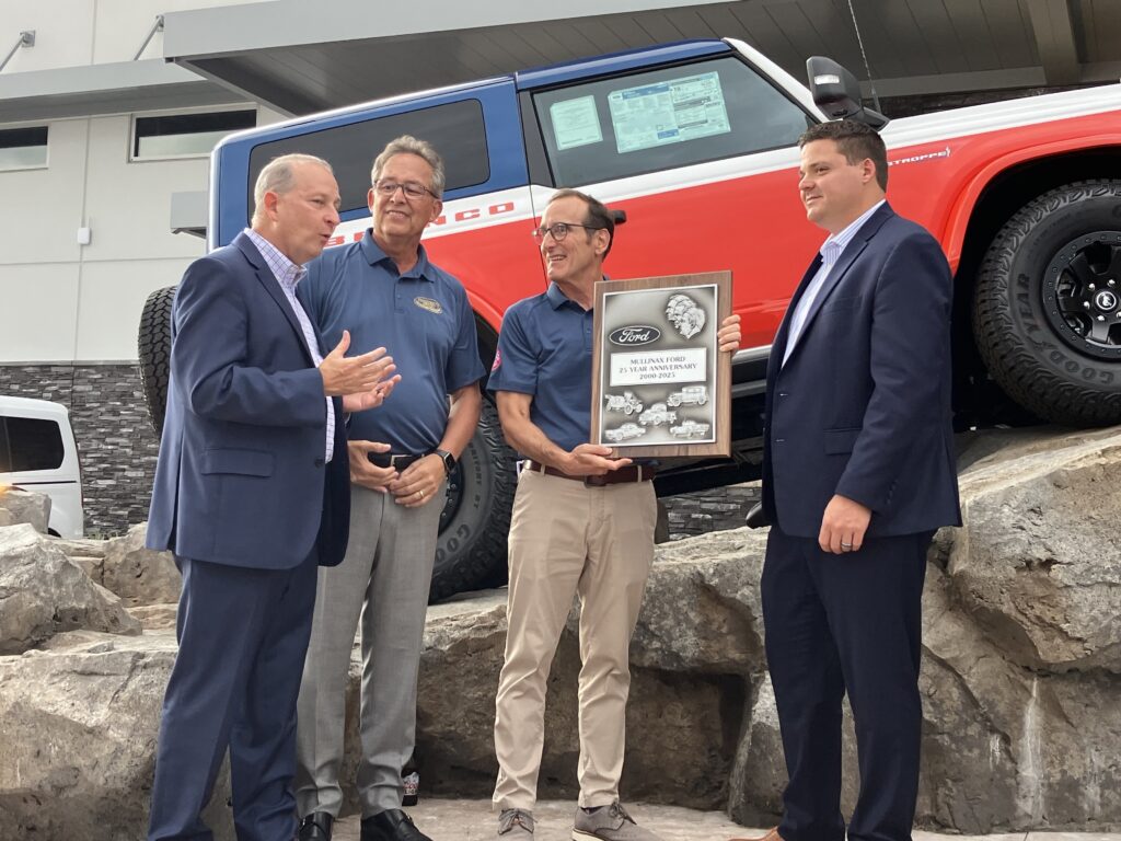 Ford officials presented Jerry Mullinax (holding plaque) with a commemorative plaque in recognition of the dealership's 25th anniversary.