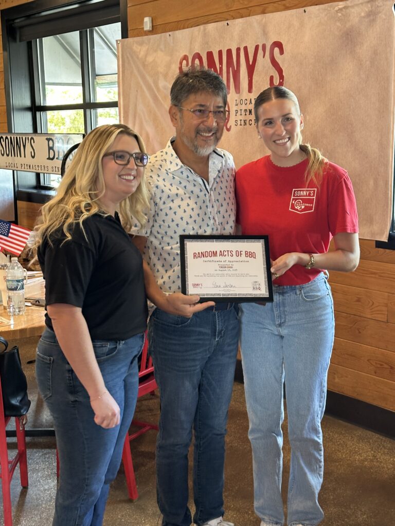 Sonny's BBQ PR staff Montana Coleman and Elena Santana pose with Tenison Shirai.
