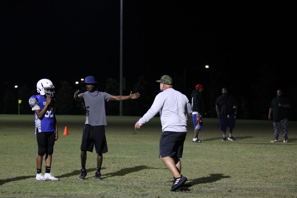 Coaches instruct the linebacker on filling the gap