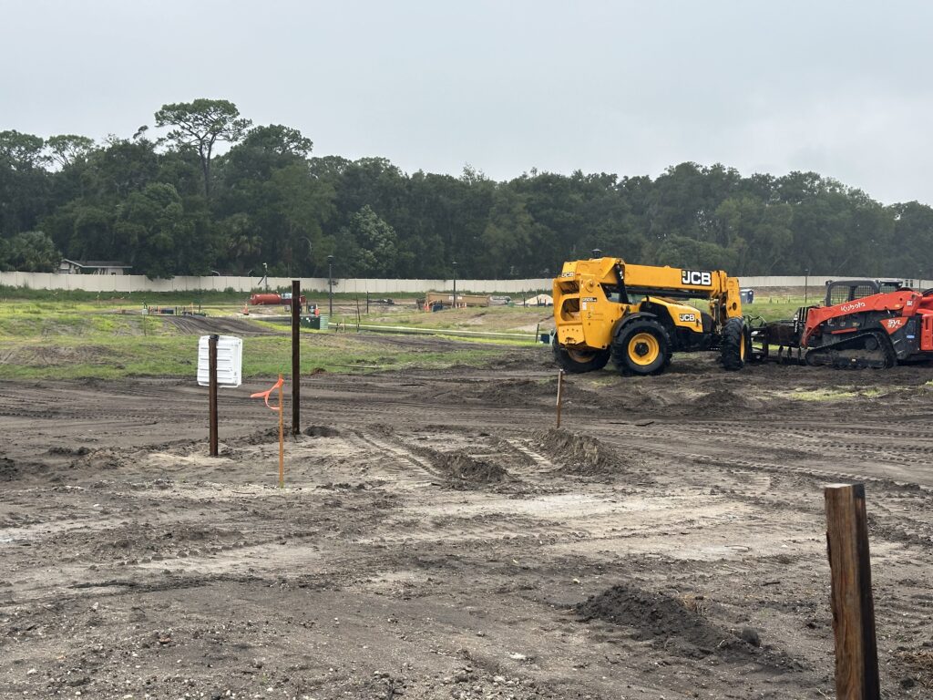 A construction site, with dirt ground and heavy machinery.