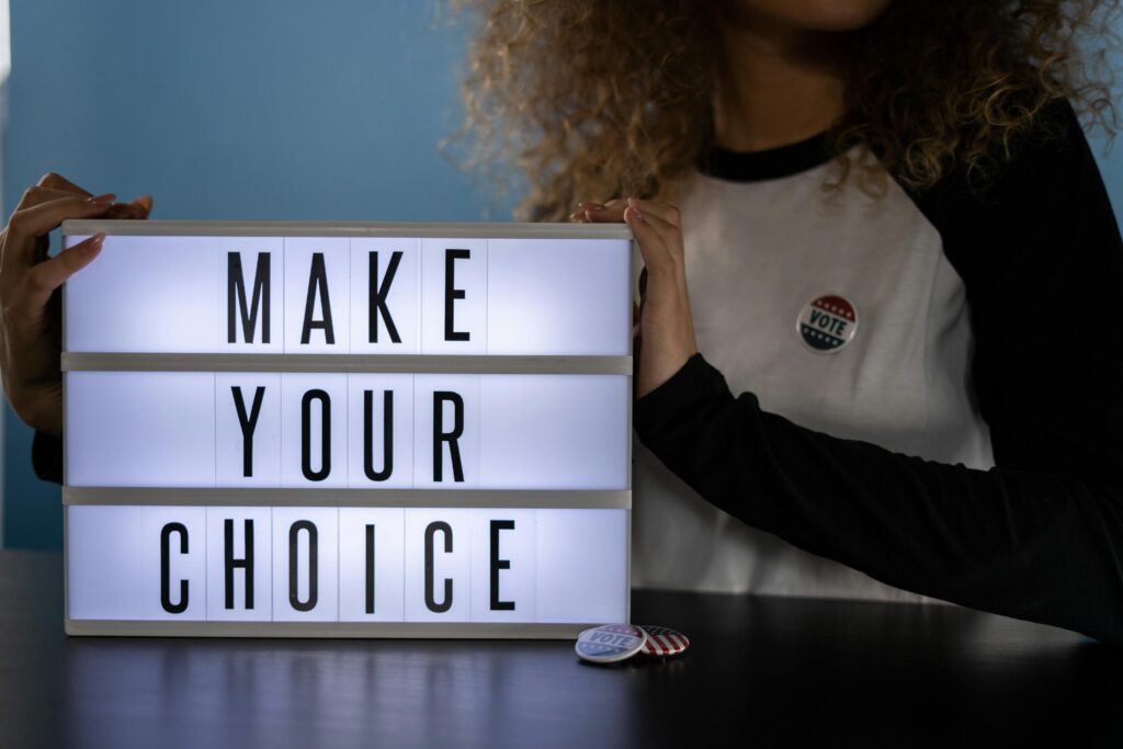 Woman stands with sign that says "Make Your Choice"