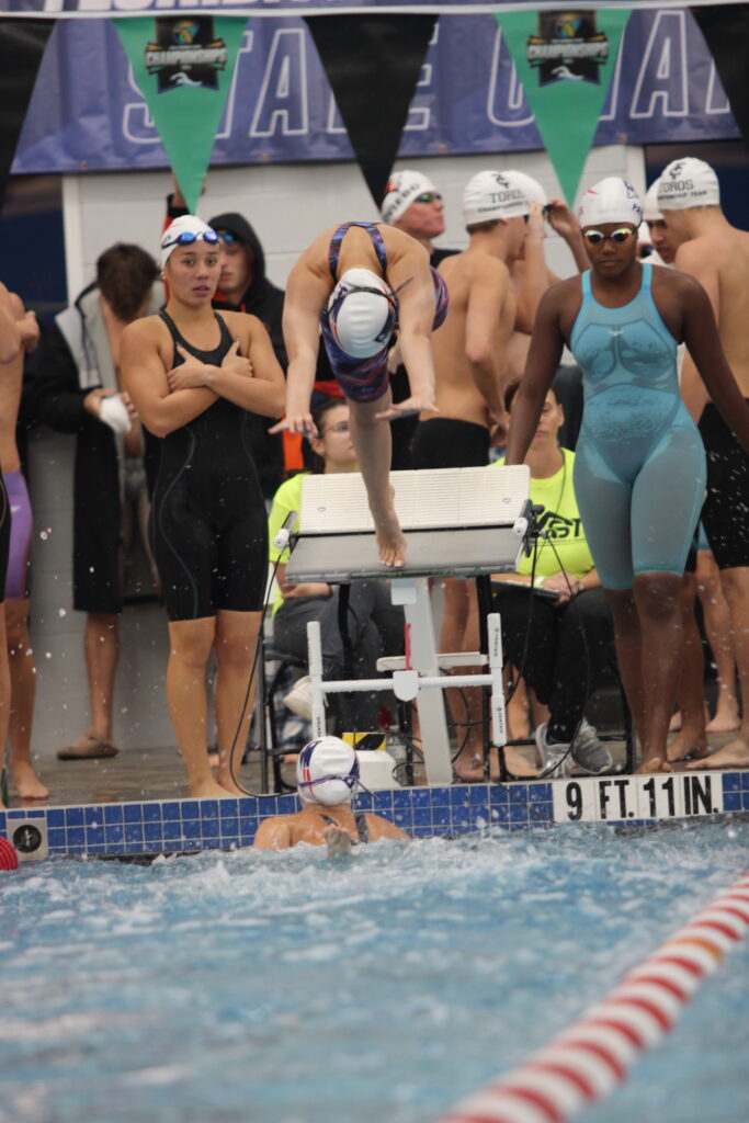 Druck propels herself into the water as the third swimmer in the 200 free relay