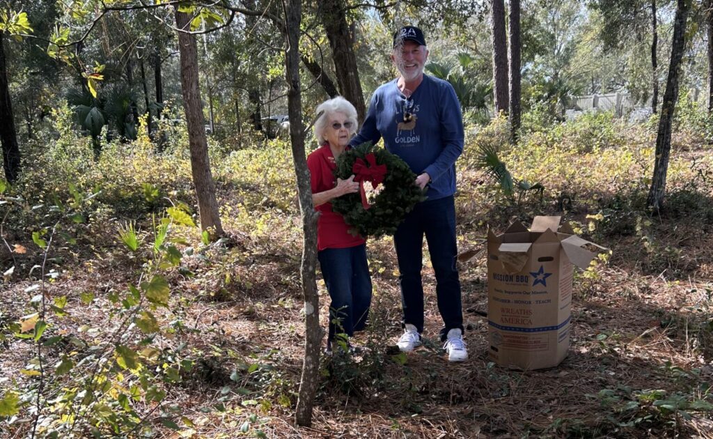 Nancy Yeager (left) and Eric Mock prepare to lay a wreath at the Bay Ridge Cemetery in the December 2024 ceremony.