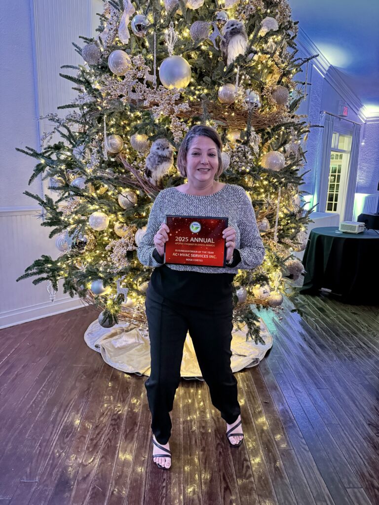 Businesswoman of the Year award winner Rosa Cortes poses with her plaque in front of the Christmas tree.