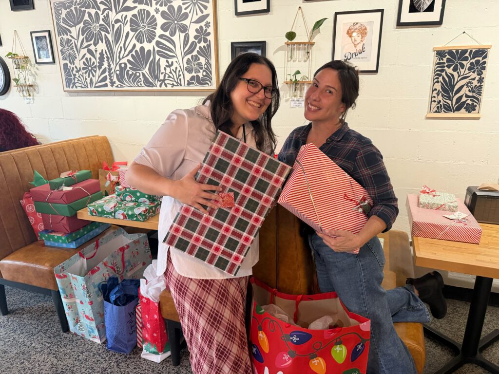 Ella Duke (right) and Sasha, an Apopka High School volunteer, smile with gifts for 150 children.
