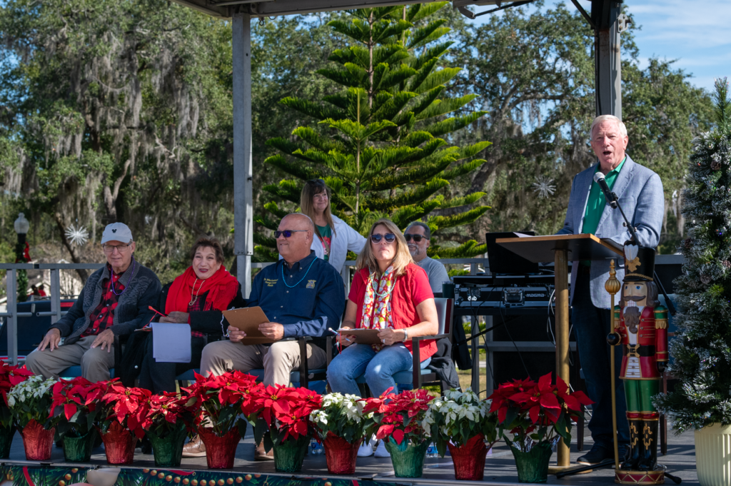 Pat McGuffin introduces parade entries as judges observe the proceedings.