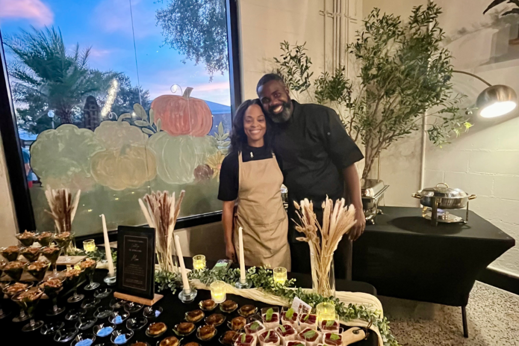 Tiffany Emerson and Dejon Emerson of Soulicious Vegan Kitchen pose behind the tasting table at The Apopka Chief's first member event.