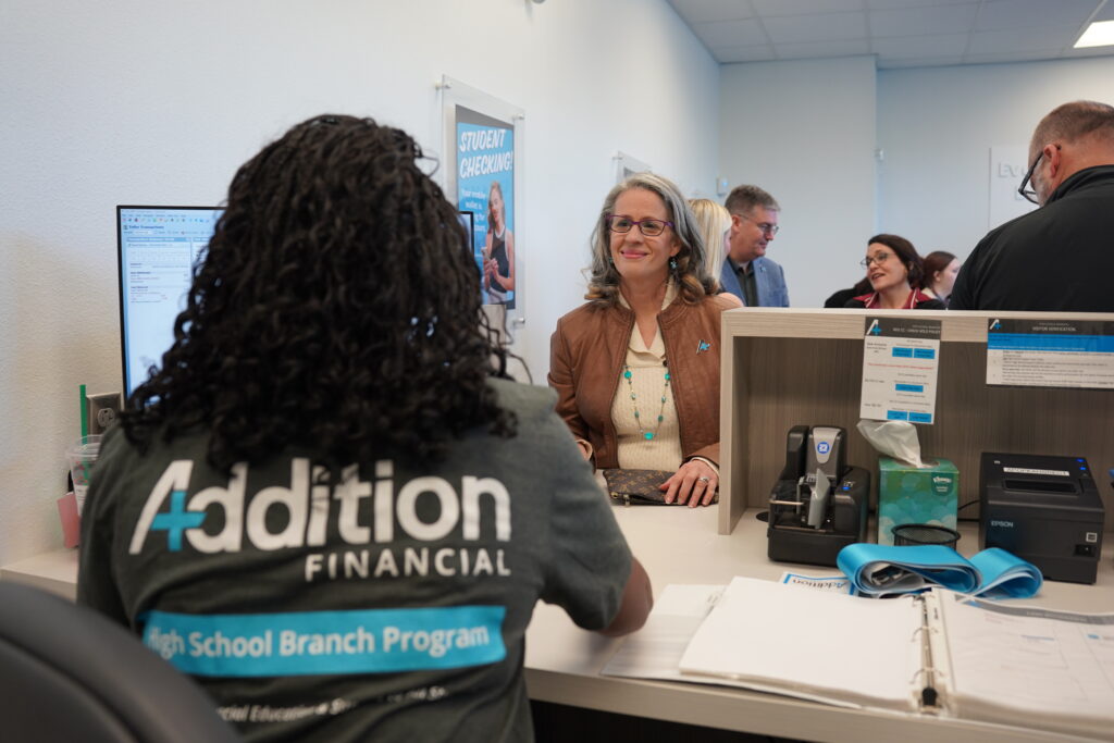 A student teller speaks with a guest.