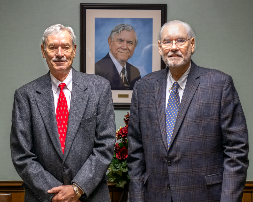 Bill McLeod and Ray McLeod pose with a portrait of their father, Johnie McLeod, at McLeod Law Firm.