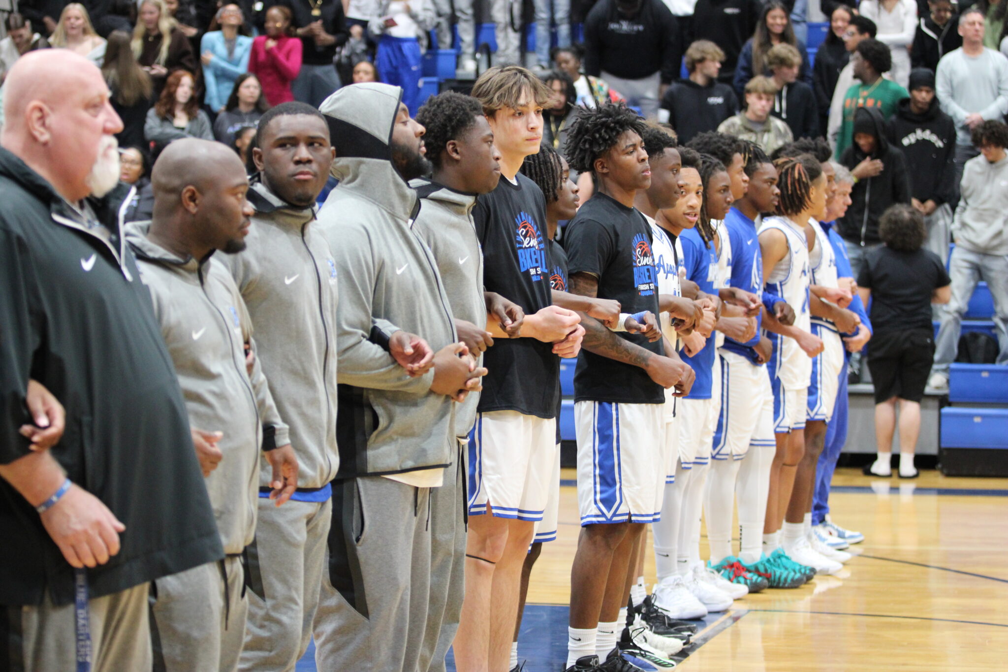 Blue Darters lock arms for the National Anthem on senior night