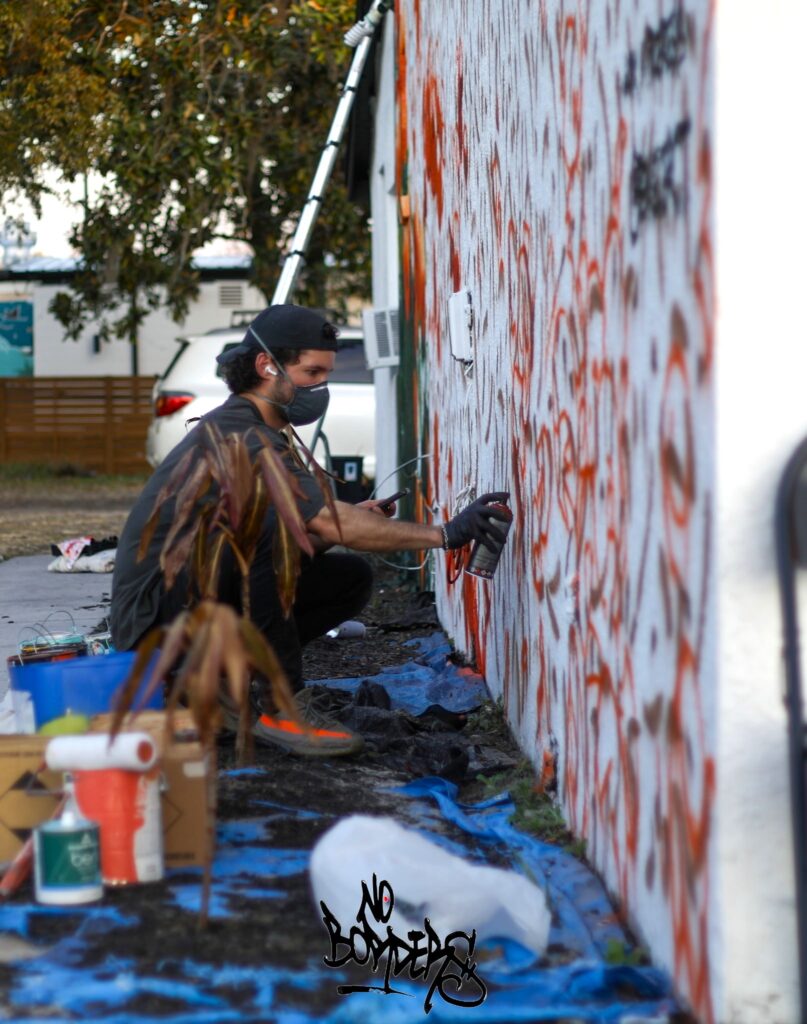 Ben Keller works on his orange grove mural before flying back to Connecticut.