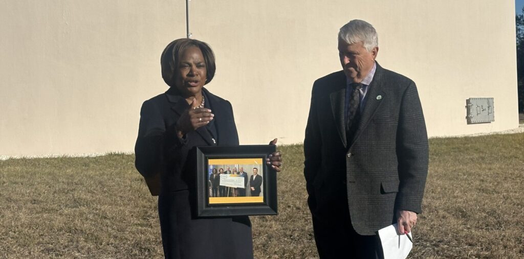 Mayor Bryan Nelson presents a framed group photo of Val Demings with the large check that she secured from Washington D.C. when she was congresswoman. The photo included Apopka city officials.