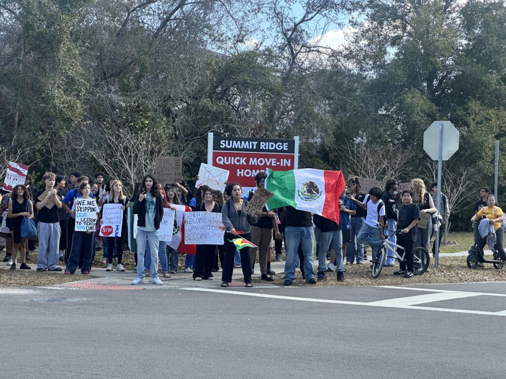 Apopka High School students stand on the corner of Maine Avenue and Martin Street, across from their high school, in a walkout event to protest ICE operations.