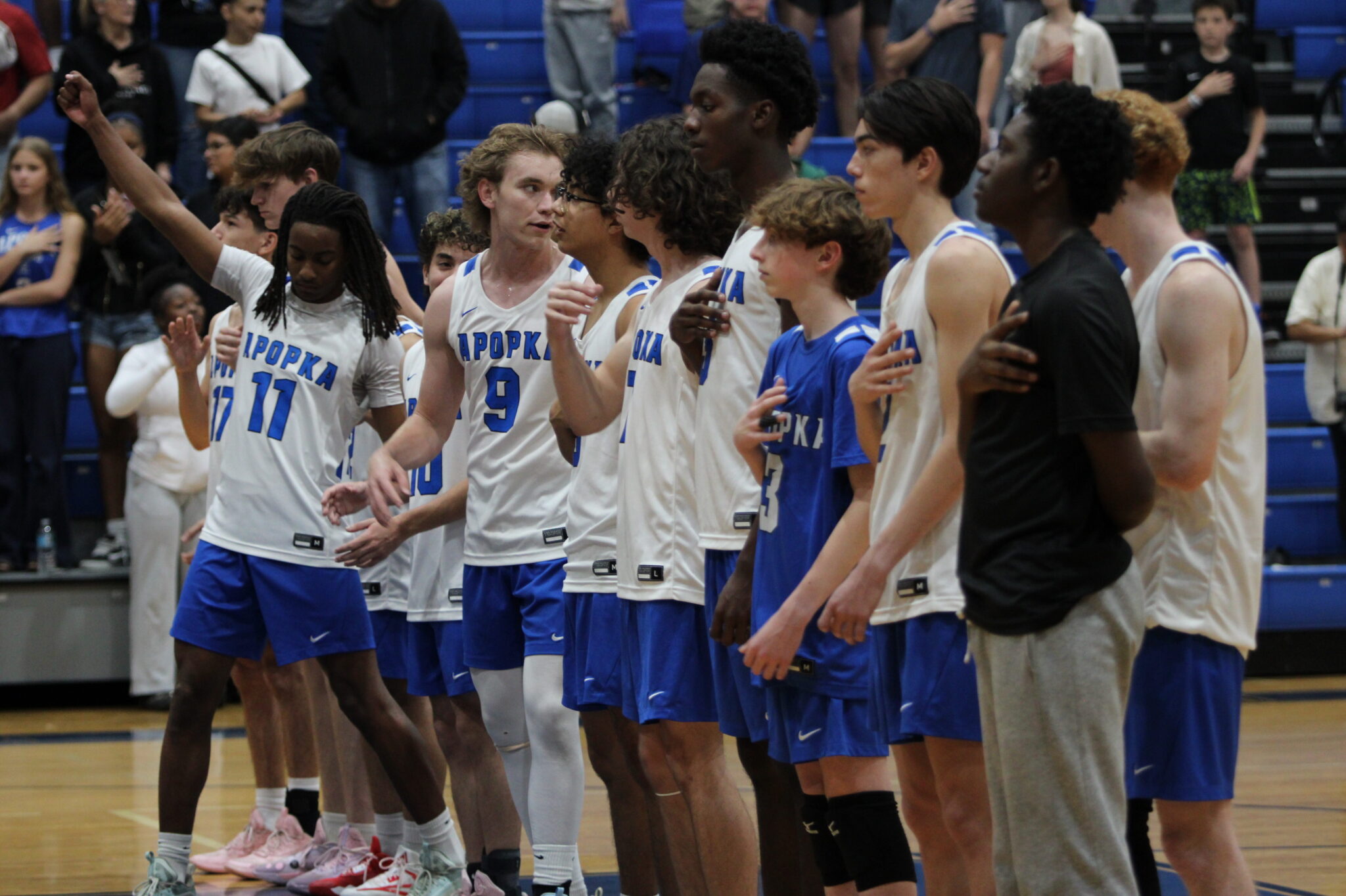Blue Darters volleyball salutes the flag ahead of their matchup against Forest Lake Academy