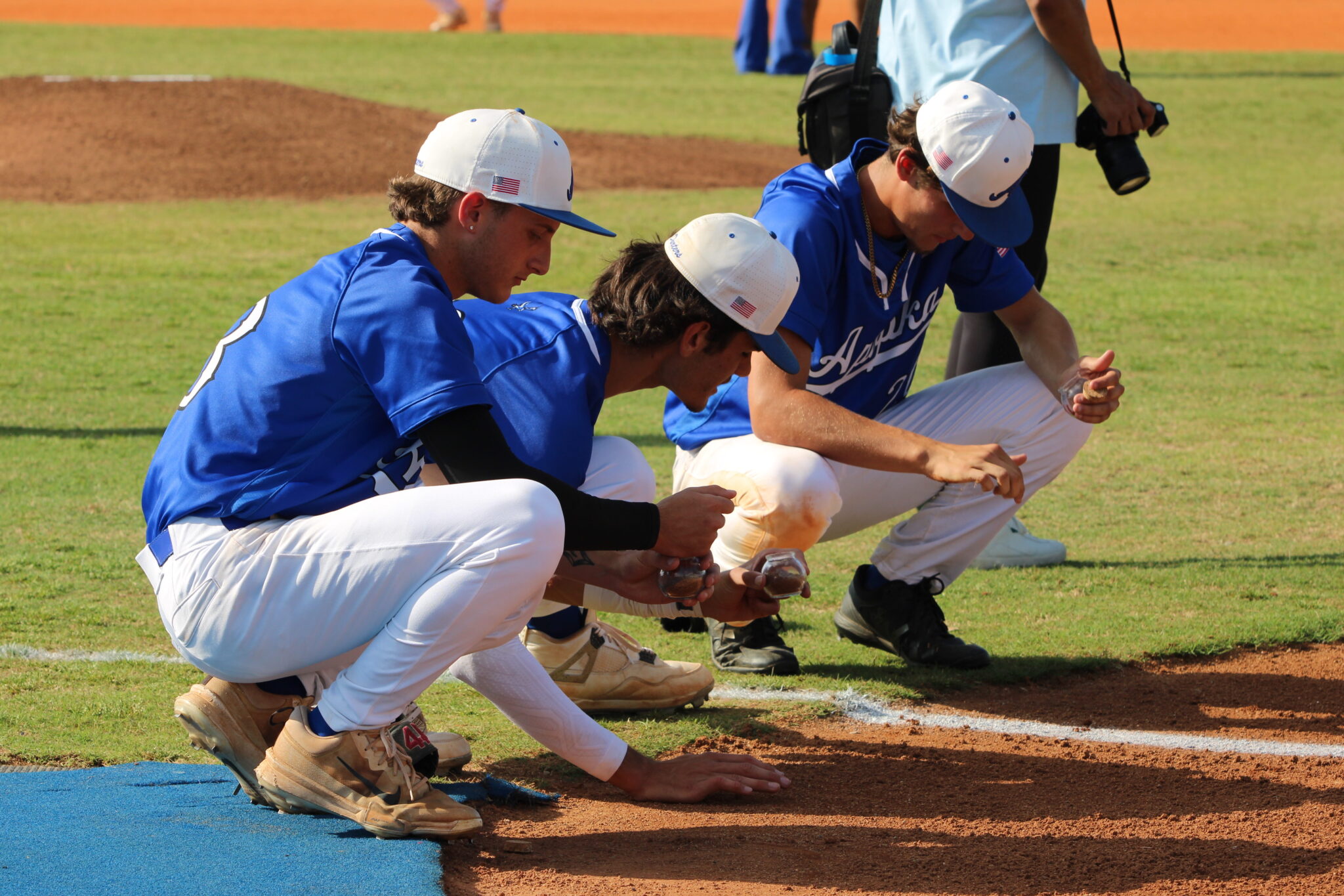 Bryce Doss, Tyler Spaid, and JD Edge collect dirt from the third base line and side of the plate they hit from as a Blue Darter