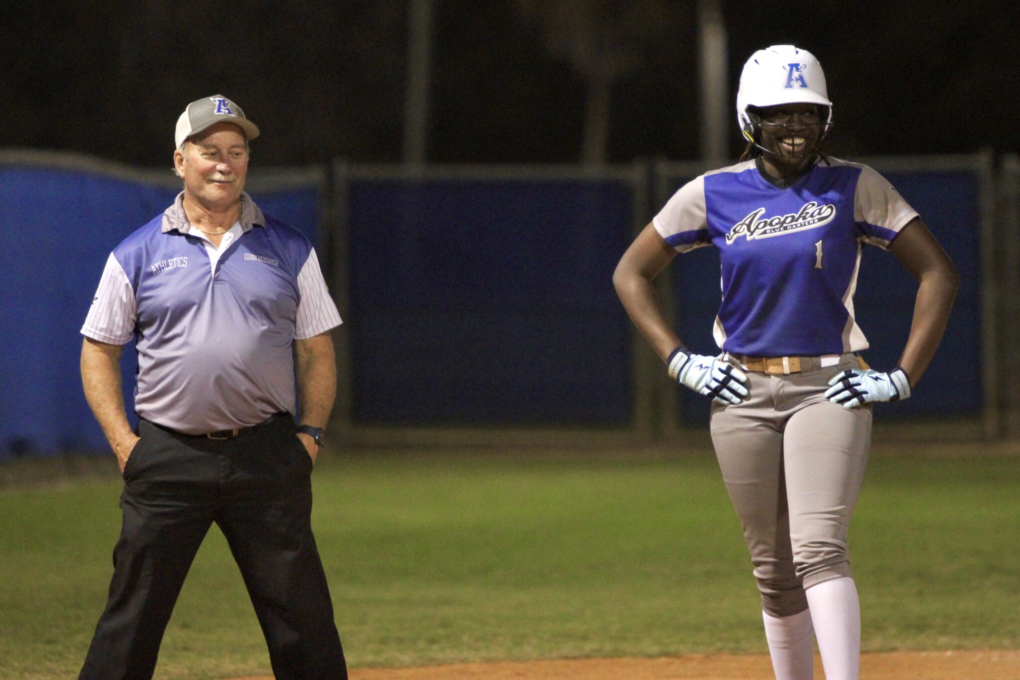 Coach Mike MacWithey and Taylor Smith share a laugh at third base after she stole the bag in the first inning