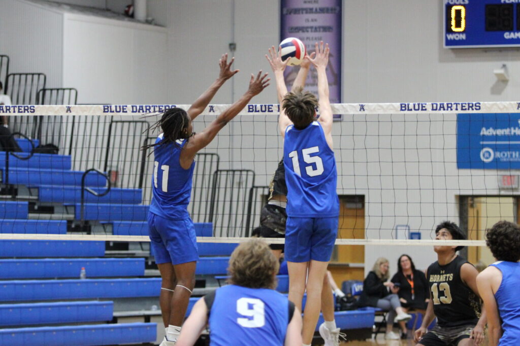 Elzie Robinson (11) and Ian Cottman (15) meet a Hornet at the net to block the kill attempt