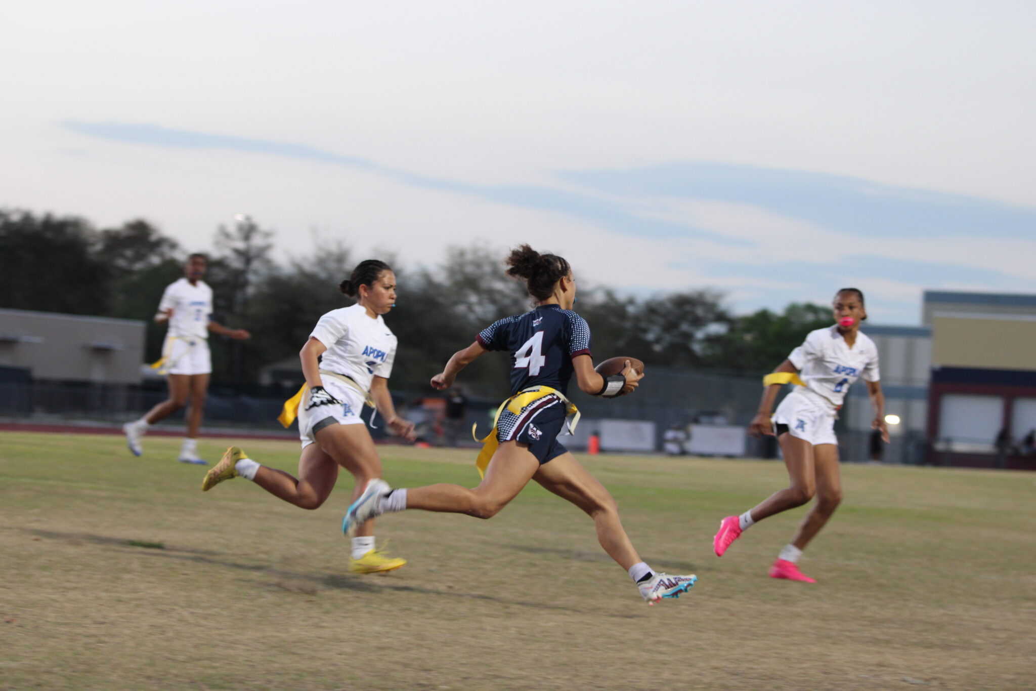Kiamora Antrum scrambles to the right sideline and is met by Blue Darters Paola De Jesus and Paeton Oliphant