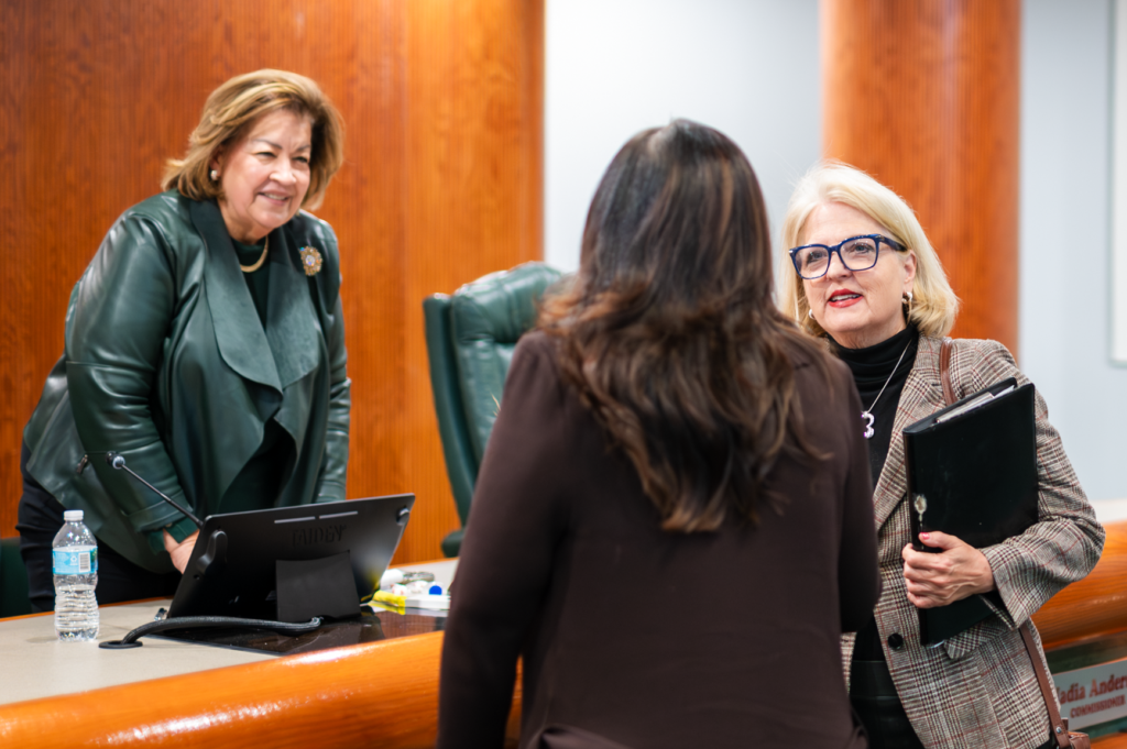 Christine Moore (R) speaks with someone at March 18 Apopka City Commission meeting as Vice Mayor Diane Velazquez (L) watches. 