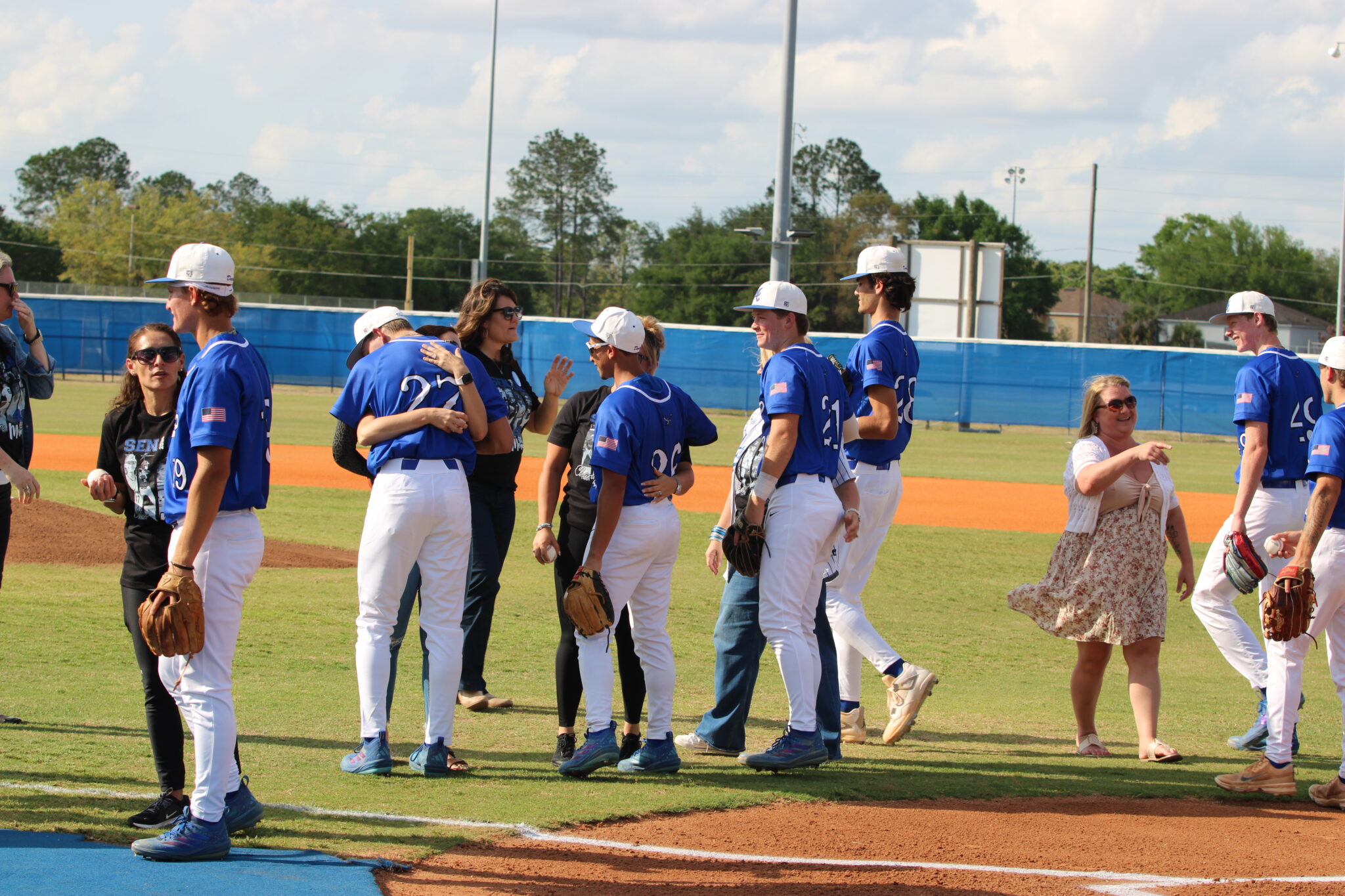 Players gather with their mothers after the first pitch on senior night