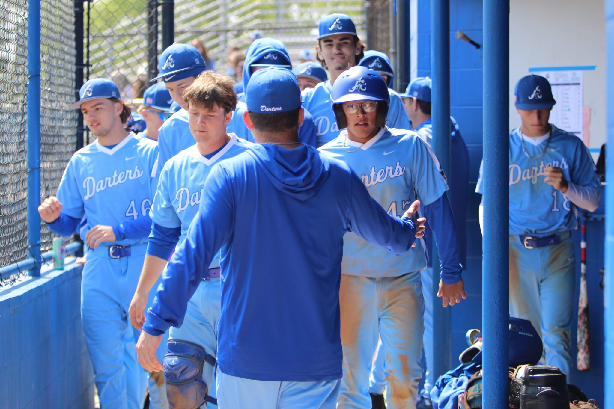 Ty Livingston walks through the dugout after scoring the opening run for the Blue Darters