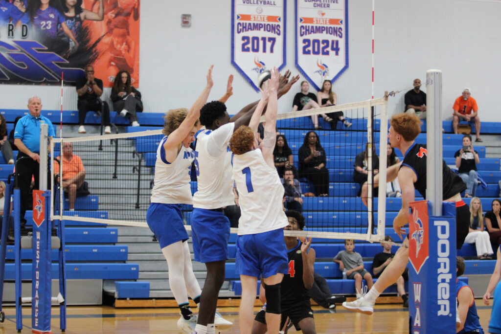 Caden McGatha, Giovanni Lubin, and Nathan White work in a collective effort to block a kill attempt early in the game