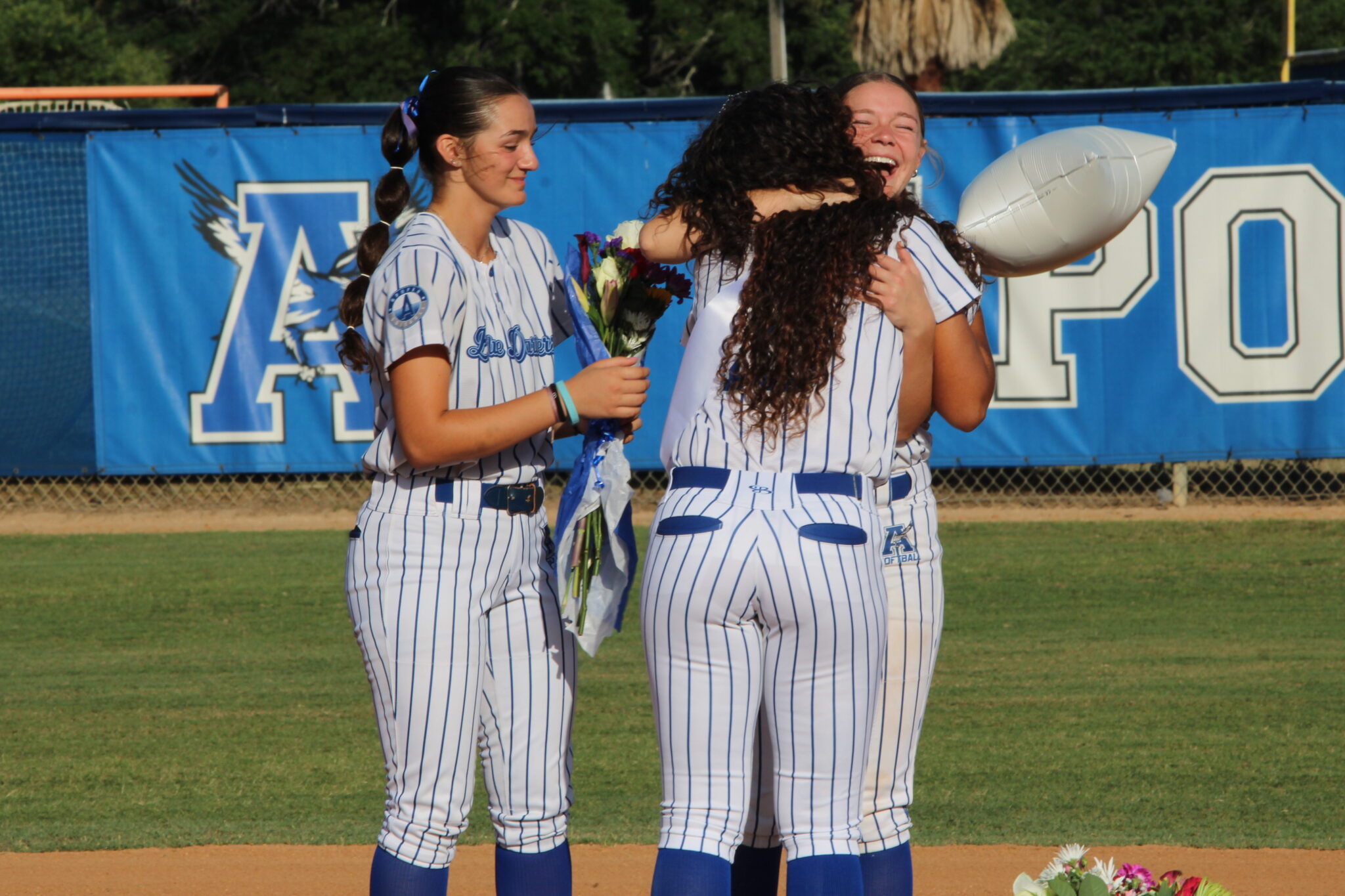 Callie Sowers and Braylyn Pirillo greet Victoria Shaw at second base with hugs and flowers
