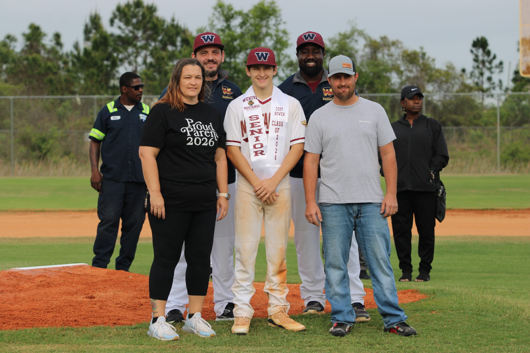 Cody Bowen poses with his family and coaches for senior night