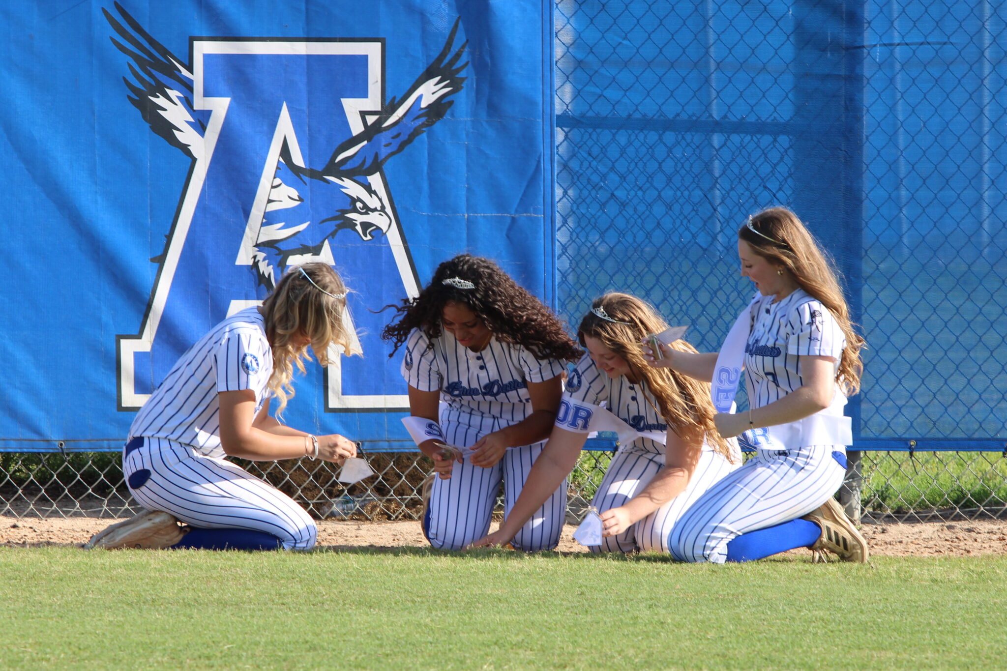 Hagan McGatlin, Victoria Shaw, Alezia Hatcher, and Haylee. Thames collect dirt in memorial of their time spent on the field