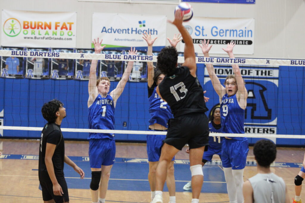 Nathan White, Quintin Daffron, and Caden McGatha rise up in unison for a block