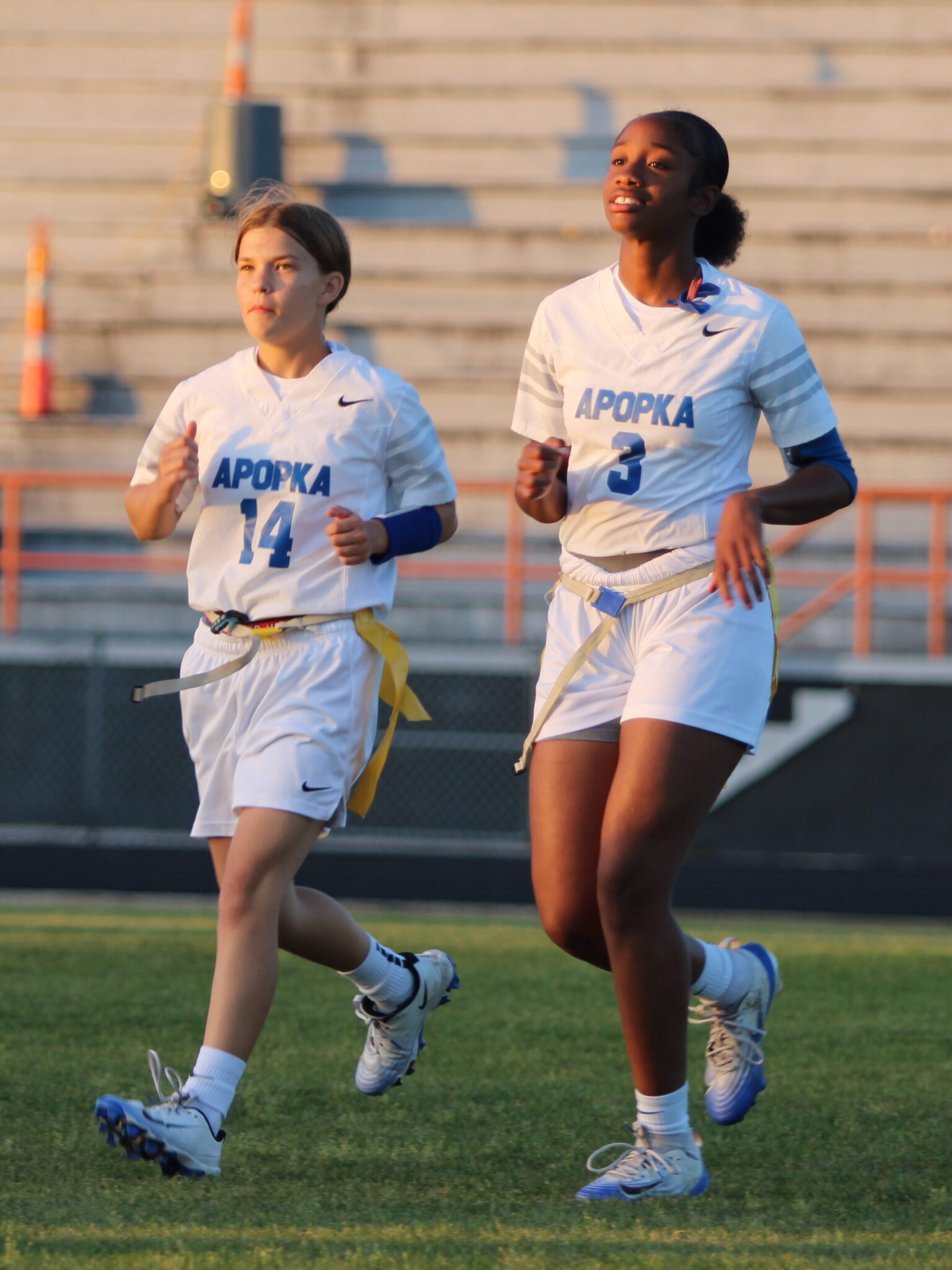 Quarterbacks Anabelle Martin and Mikayla Wiggins hustle off the field after the coin toss
