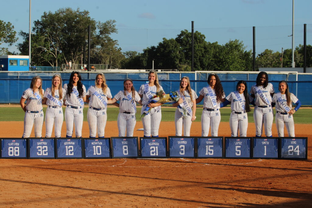 Seniors pose together across the pitchers circle for senior night