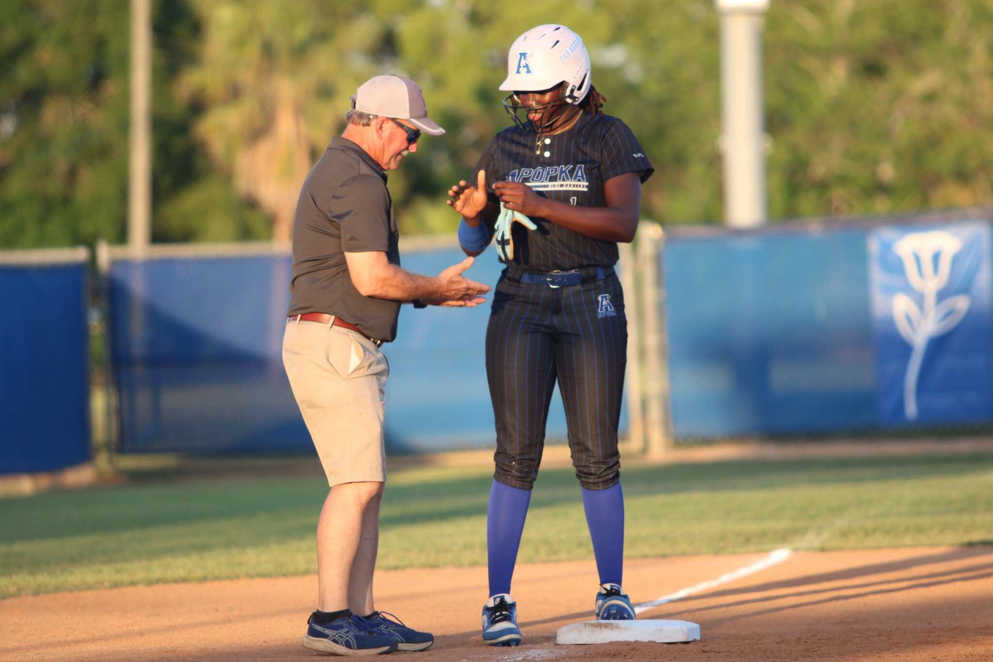 Taylor Smith meets Coach Mike MacWithey at third base after reaching safely off a passed throw to second base