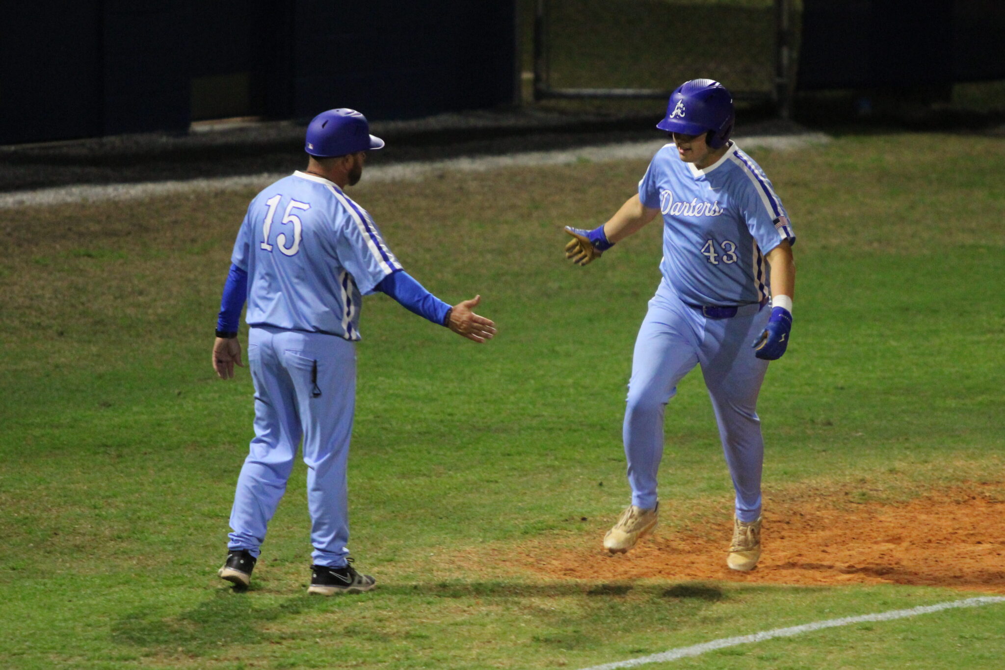 Coach Scott Garland and Anthony Raymond high five as he rounds third base on his game-ending grand slam against Wekiva