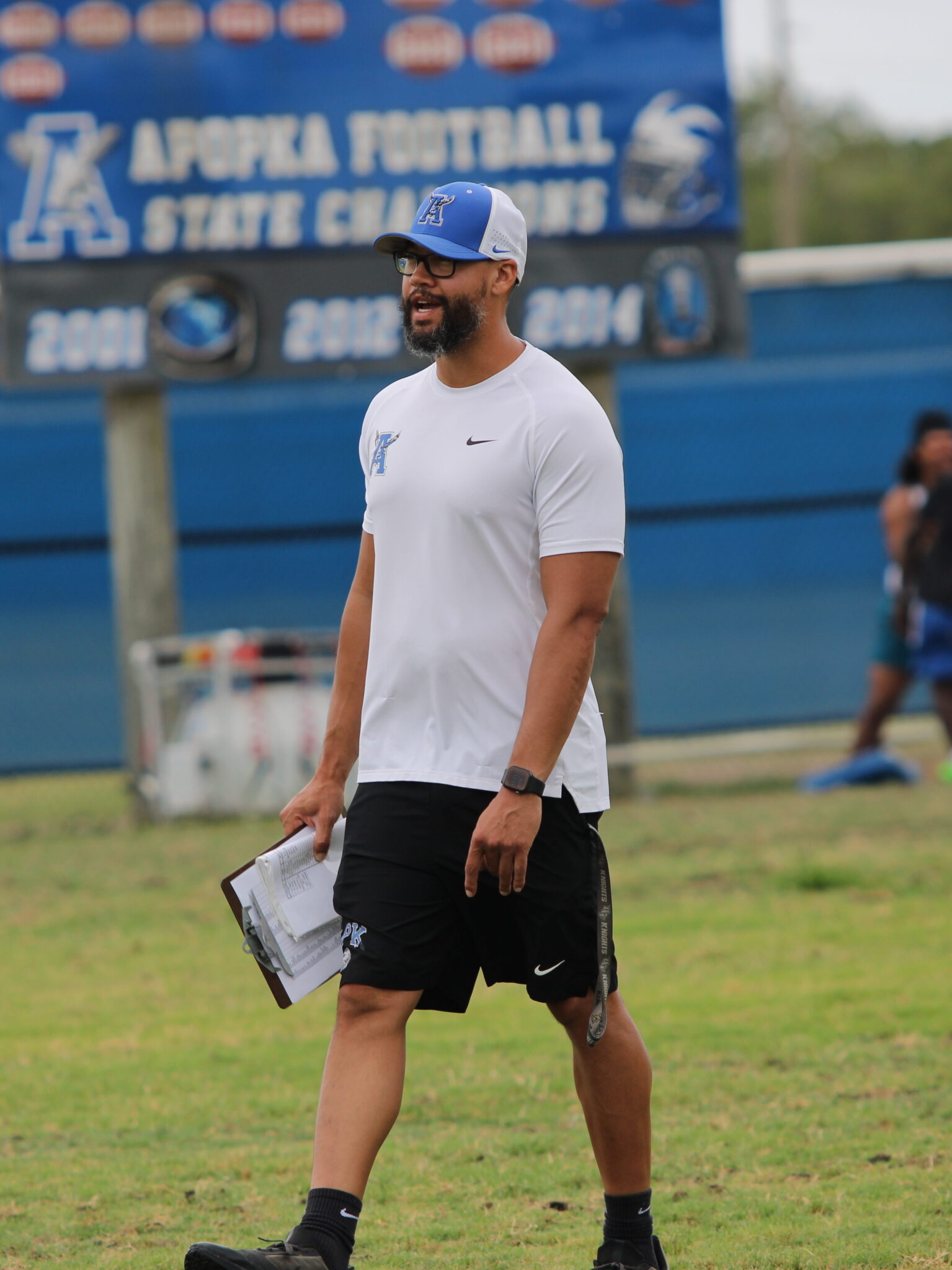 Coach Marcus Neeson checking in on each group during the on-field workout.