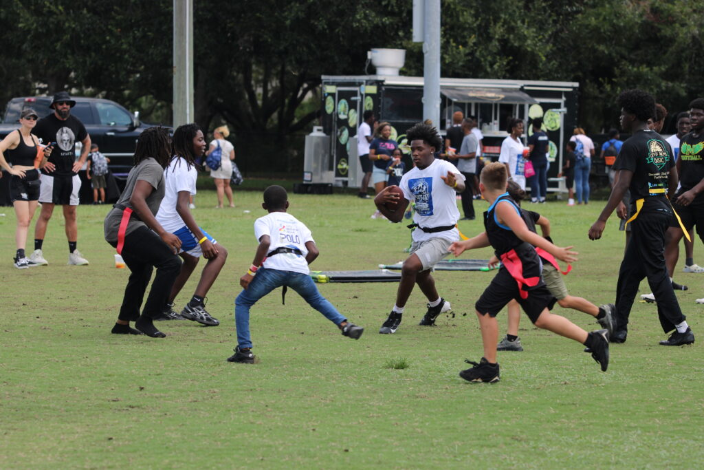 A group of kids along with AHS WR Nyzier Collington, swarm a ballcarrier during the flag football game at Apopka Community Sports Day.