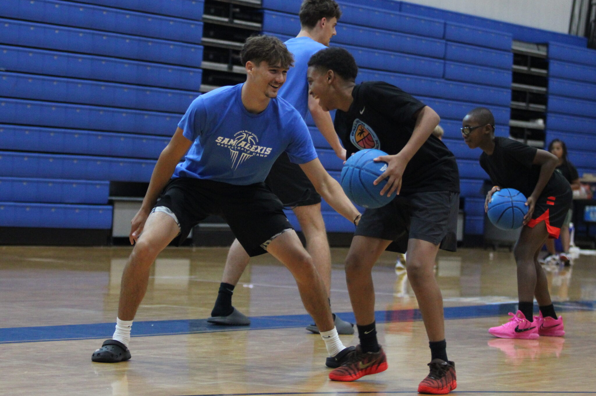 Alex Congdon guards up and smiles with a young camper.