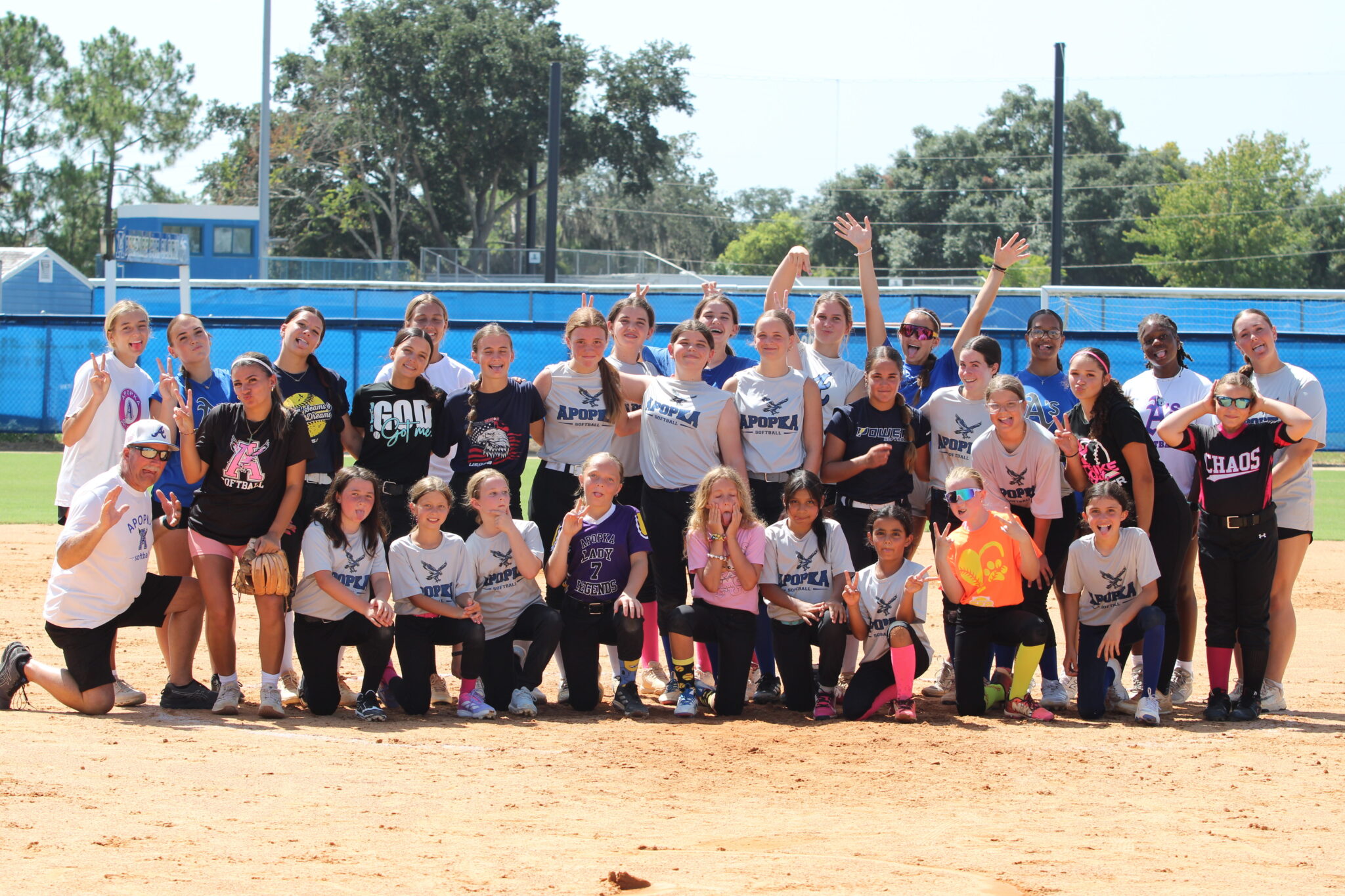 Apopka Blue Darters softball camp groups up at the pitching circle and poses for a funny picture on Wednesday at the Apopka High School softball field.