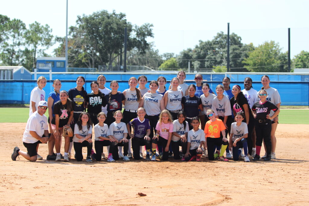 Apopka Blue Darters softball camp groups up at the pitching circle and poses for a picture on Wednesday at the Apopka High School softball field.